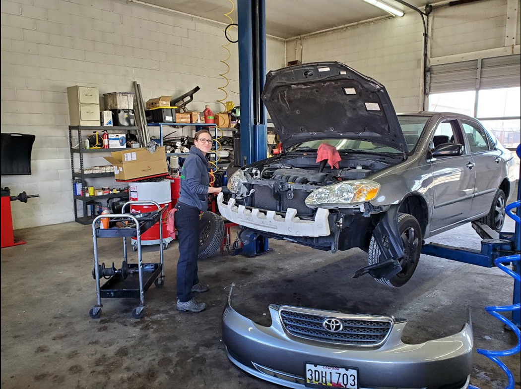 Employee smiling while repairing car